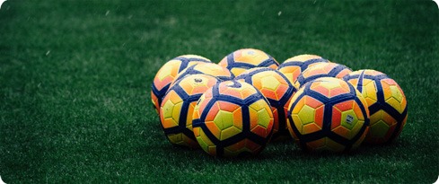 Footballs grouped together on grass