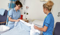 Image: two nurses changing bed sheets