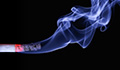 Image: a lit cigarette with smoke drifting upwards