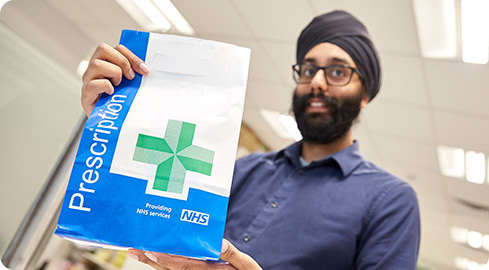 Image: Pharmacist holding an NHS pharmacy bag